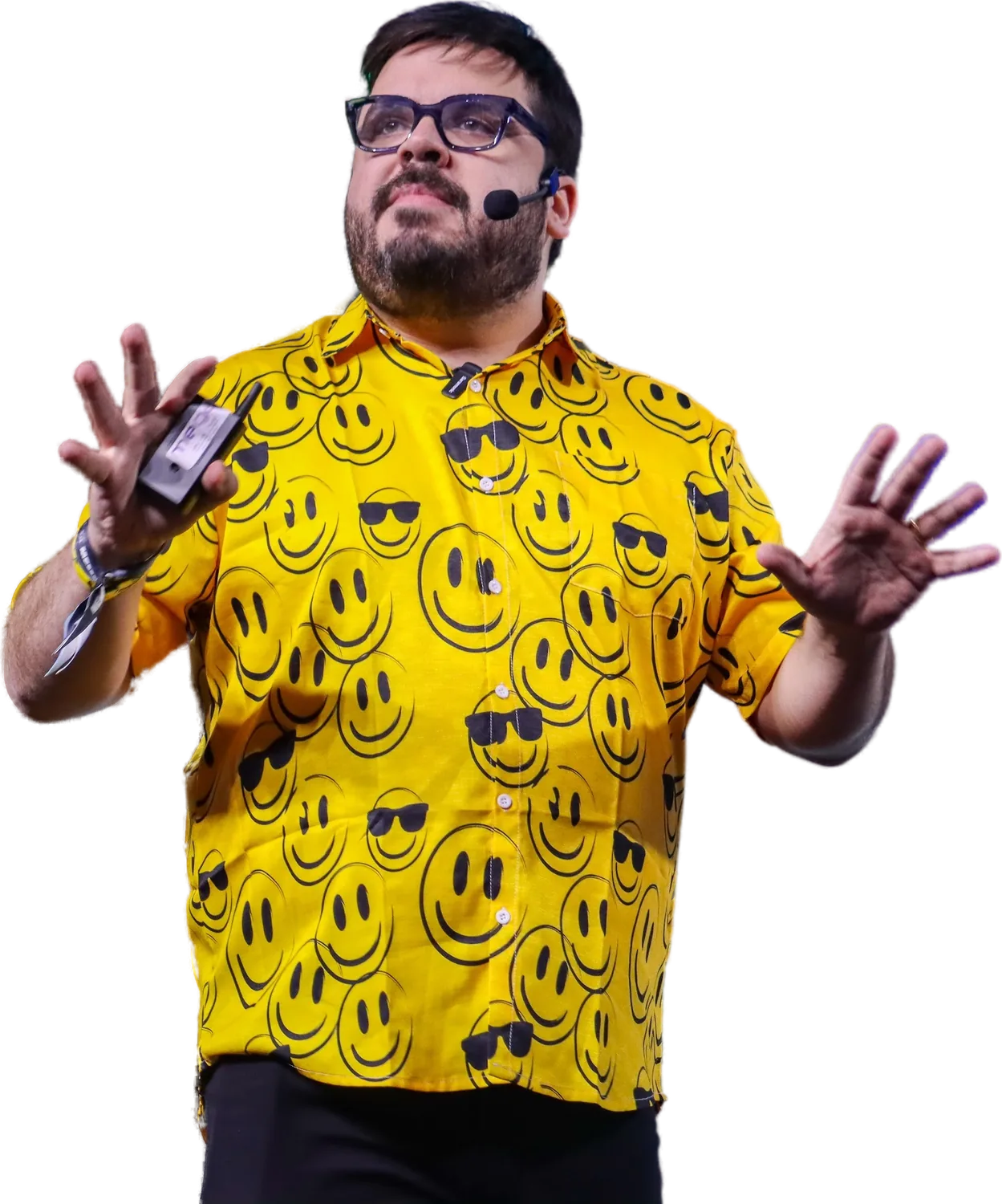 Bruno UAU no palco da HJ Conference, de camisa amarela de smileys e mãos abertas