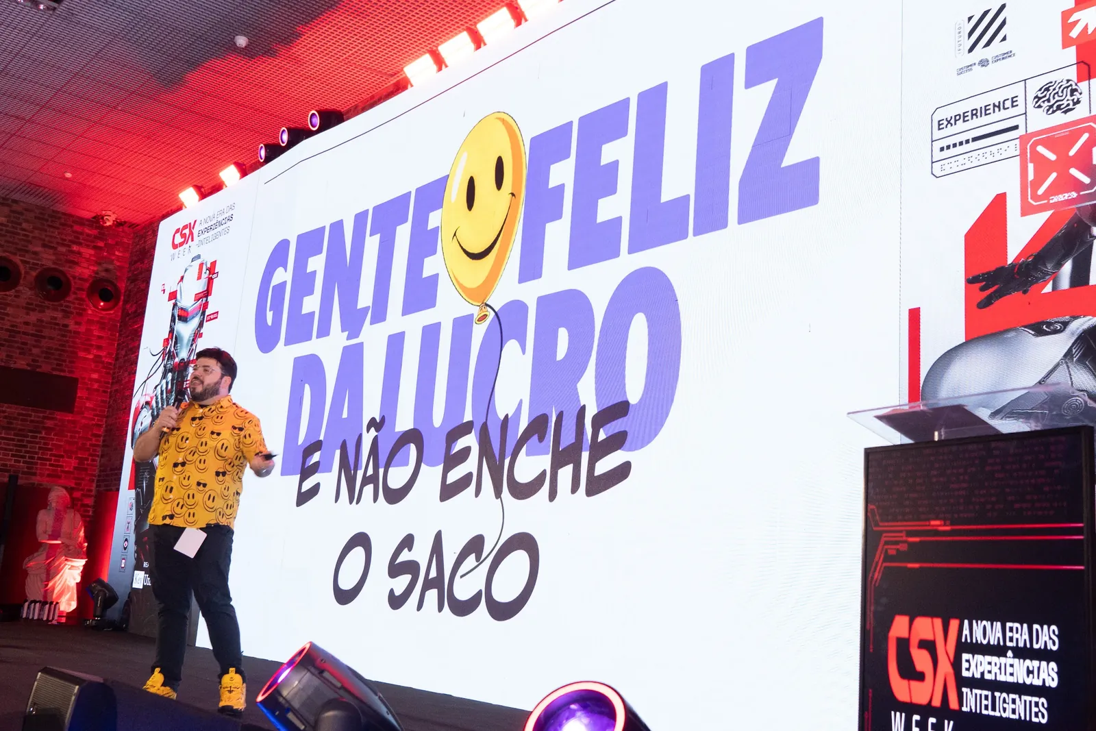 Bruno UAU diante do telão gigante com o título da palestra