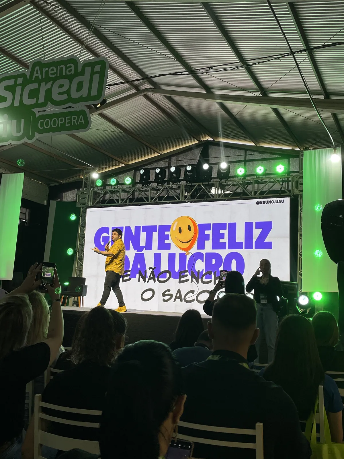 Bruno UAU no palco do Noroeste Summit, com o título da palestra no telão