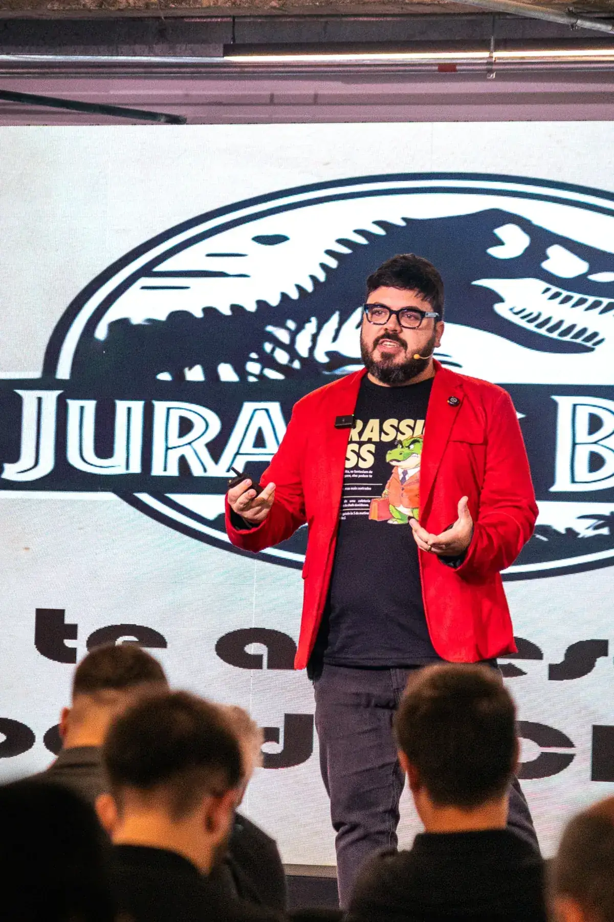 Bruno UAU no palco, diante do logo do Jurassic Boss no telão