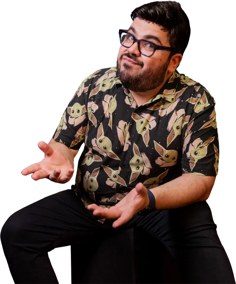 Bruno UAU sentado, de braços abertos, como quem pergunta