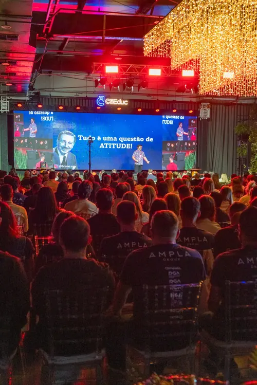 Auditório cheio, visto do fundo, com o Bruno UAU no palco